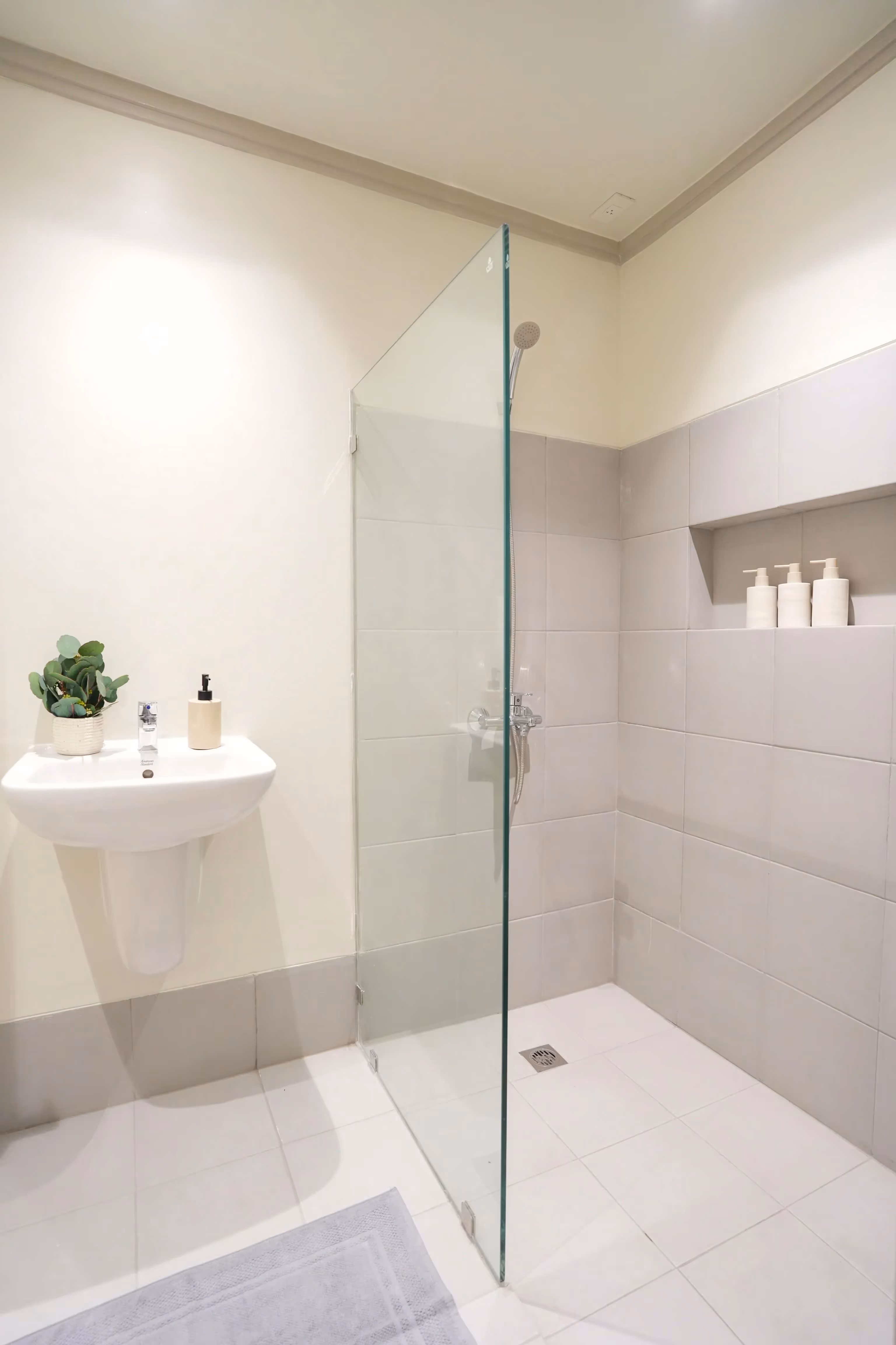 Minimalist bathroom with glass-enclosed shower and wall-mounted sink.