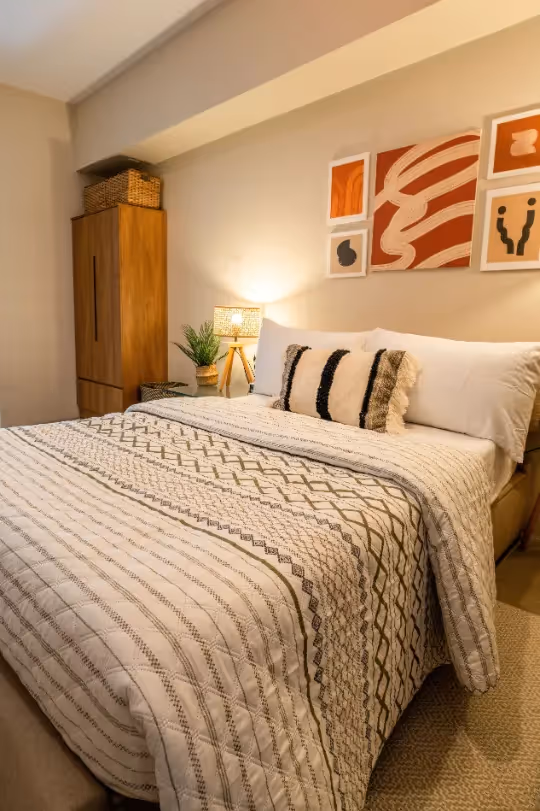 Stylish bedroom with comfortable bed and patterned throw pillows at Merano, Tierra Lorenzo Lipa.