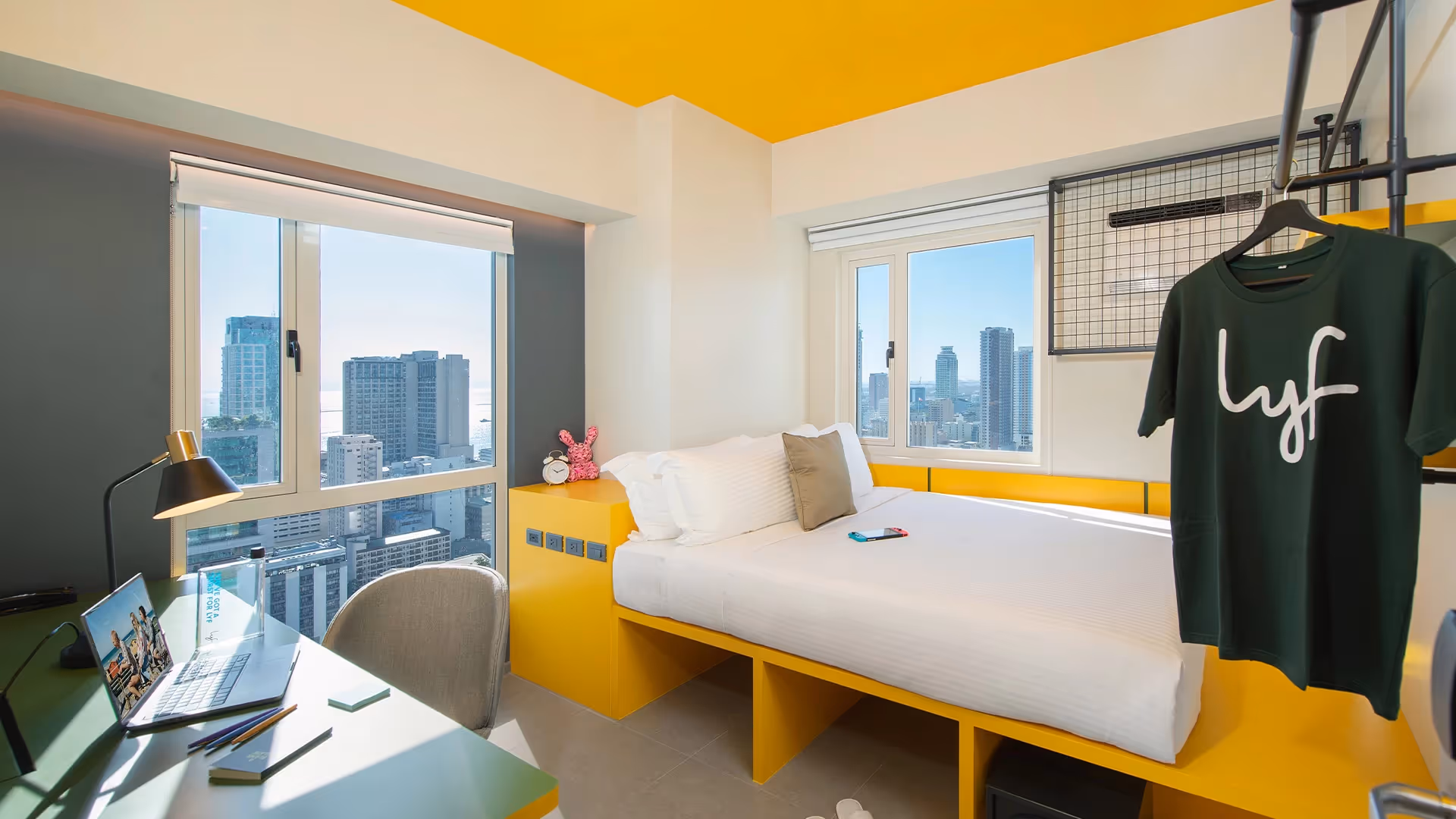 Lyf Malate bright room with a bed, desk, and city view windows.