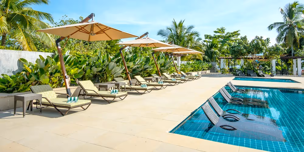 Resort pool with sun loungers and tropical backdrop at Dusit Thani Lubi Plantation Resort.