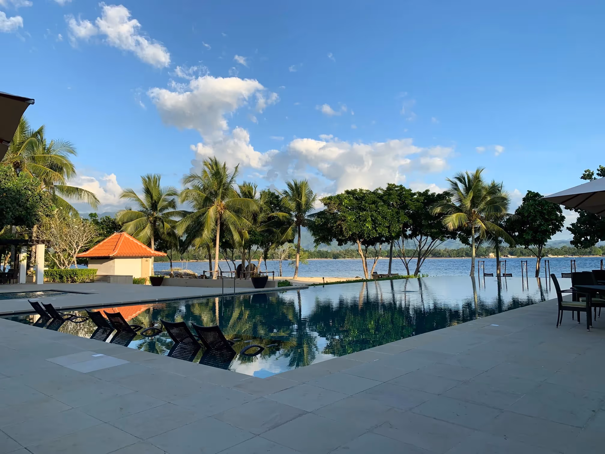 Scenic beachfront pool with calm waters and tropical surroundings at Dusit Thani Lubi Plantation Resort.