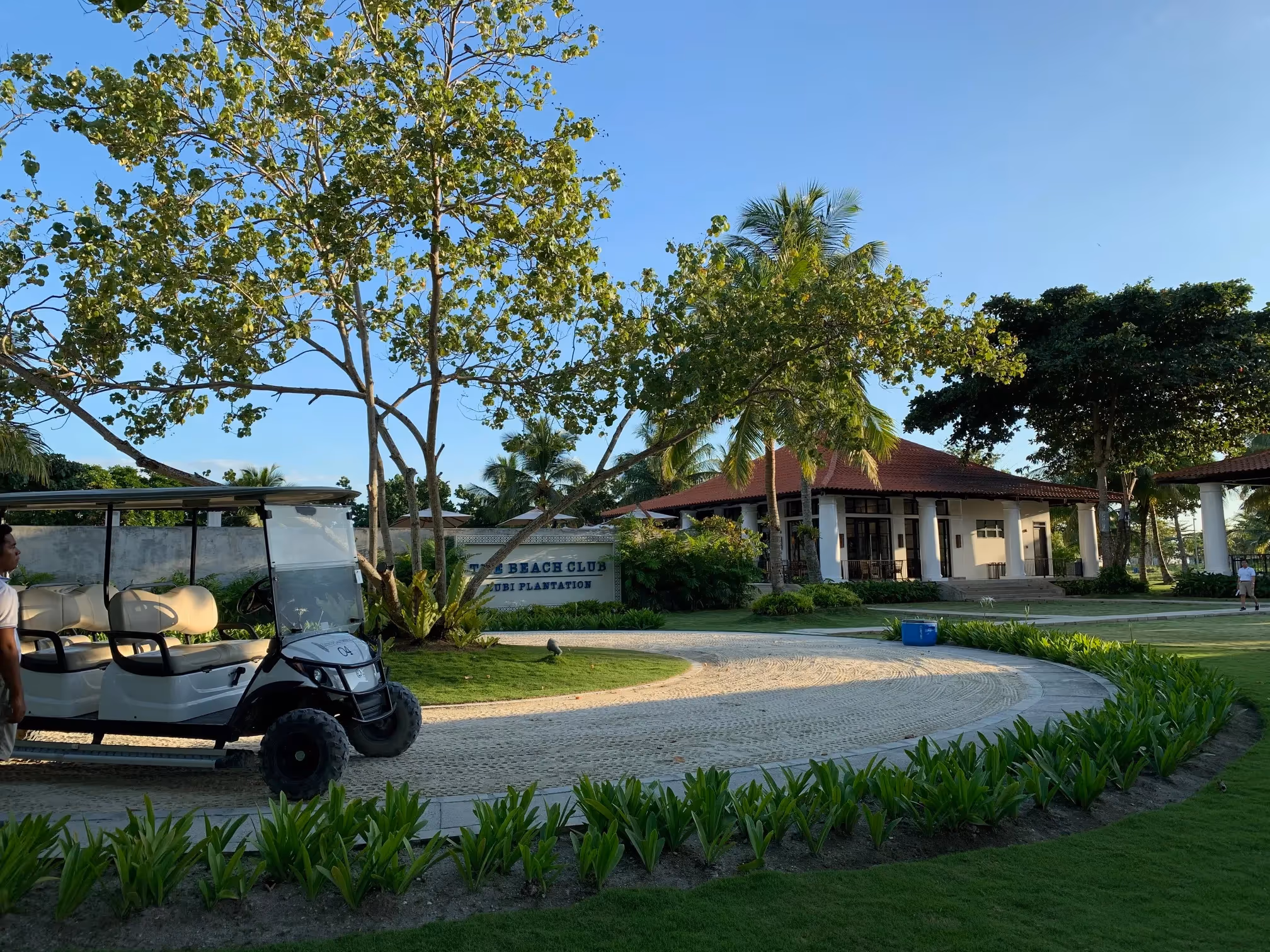 Spacious garden lawn with a walkway and shaded pavilion at Dusit Thani Lubi Plantation Resort.