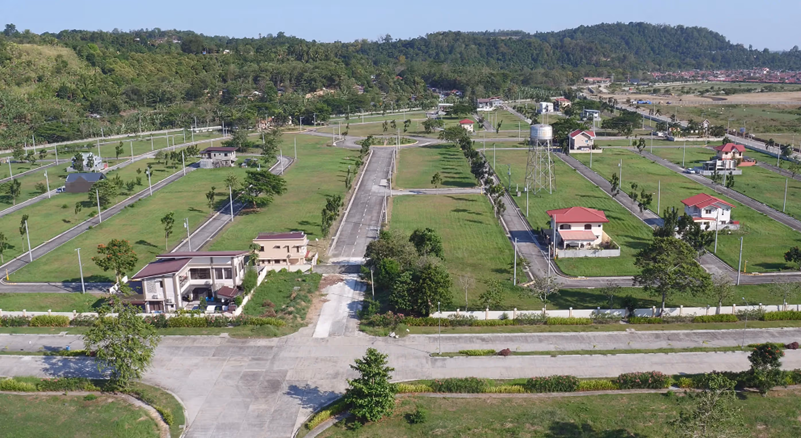 Ciudades Business Park featuring open land with scattered houses and lush green scenery in a developing area.