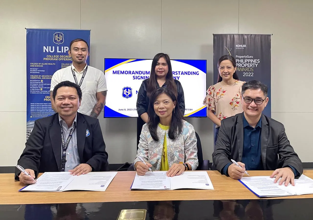 A group of people sitting at a table signing papers for NU Lipa student residences