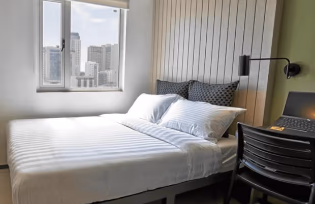 The Suites bedroom with a bed, desk and a laptop in Torre Lorenzo Malate.