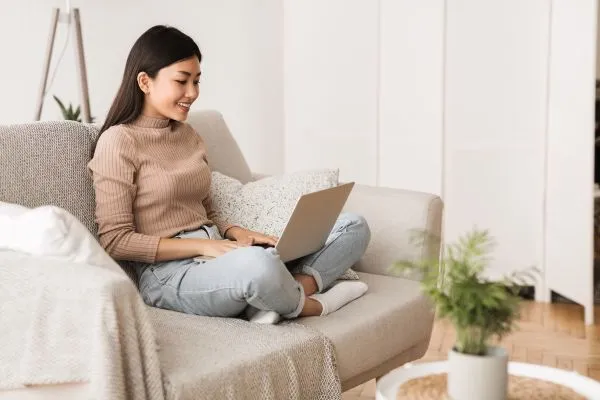 Woman using laptop while sitting comfortably on a sofa