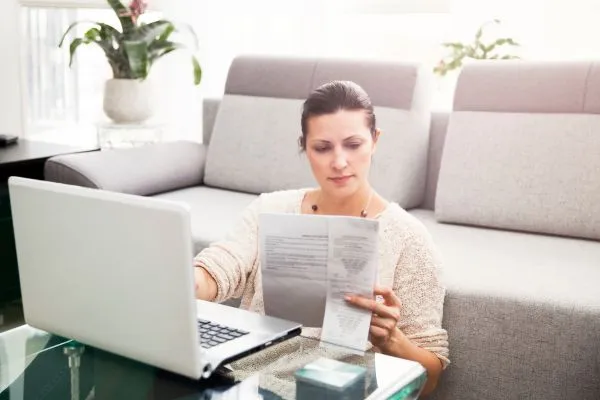 Woman reviewing bills in front of a laptop