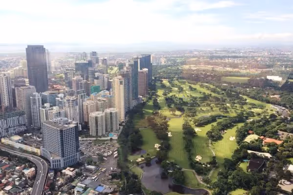 Aerial view of city skyline beside large green golf course.