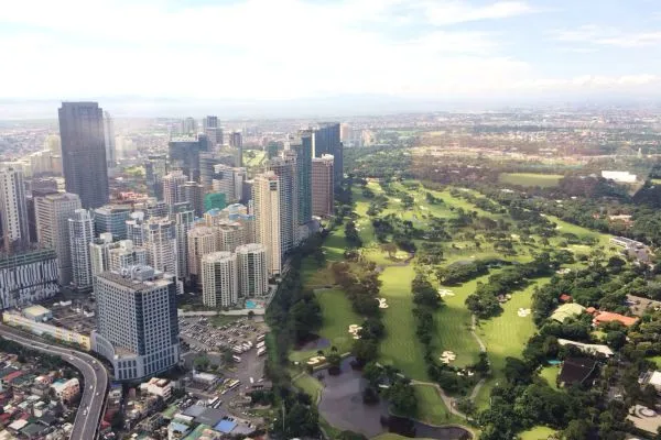 Aerial view of city skyline beside large green golf course.