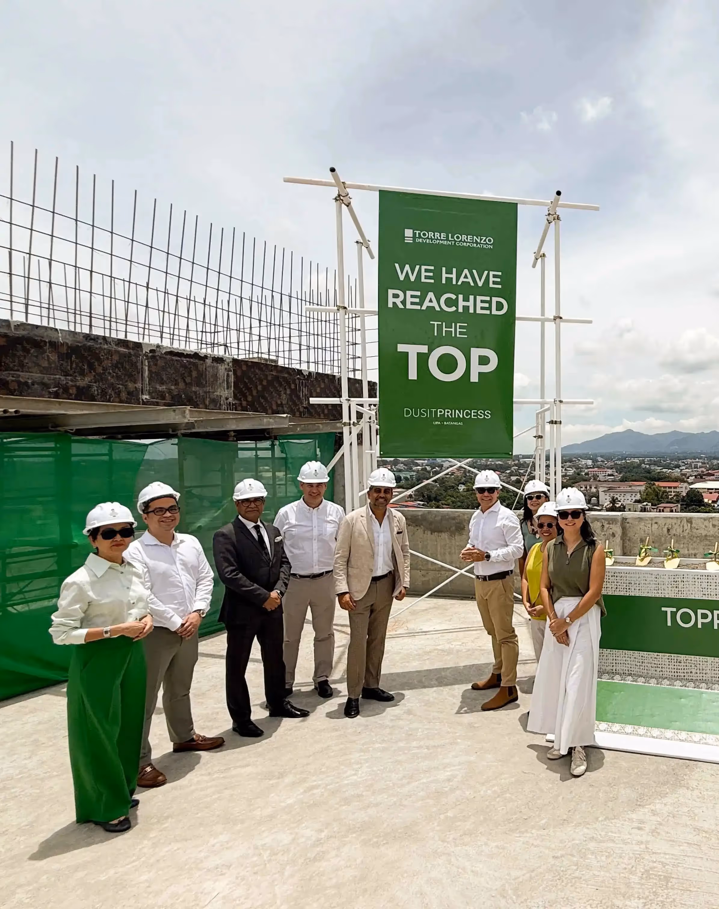 Project team posing under We Have Reached the Top banner at construction site