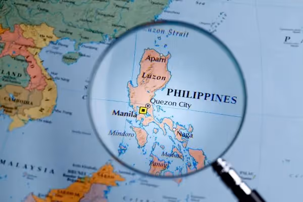Magnifying glass highlighting the Philippines on a world map.