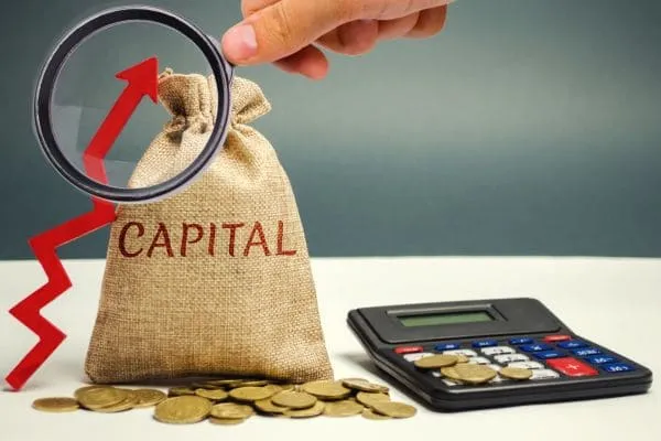 Money bag labeled capital with coins, calculator, and red growth arrow