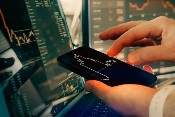 A hand holding a smartphone displaying a stock market chart