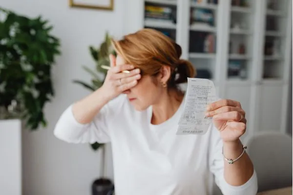 A woman presents a paper in front of her face, potentially addressing condo living costs.