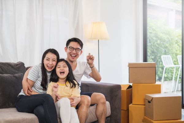 A family sits on a couch surrounded by moving boxes in a Davao condo, symbolizing their new home journey.