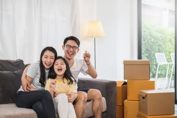A family sits on a couch surrounded by moving boxes in a Davao condo, symbolizing their new home journey.