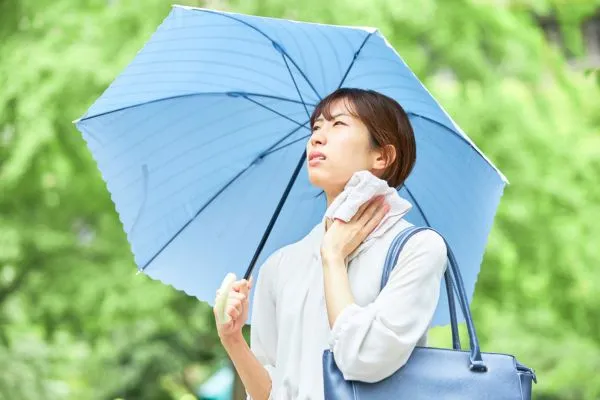 A woman holding an umbrella stands in the rain, embodying summer condo living amidst a wet, vibrant atmosphere.