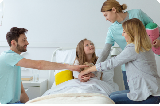 Adolescente sentada en una cama de hospital junto a su familia y personal de salud, acompañándola y dándole apoyo.