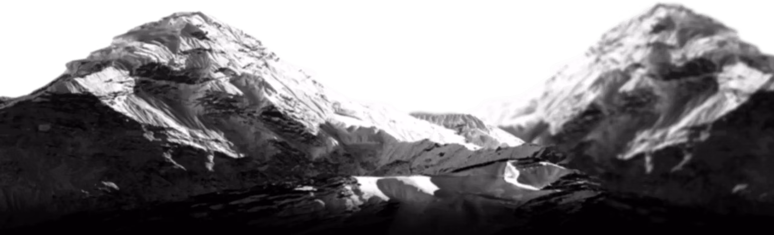 Schwarz-weiß-Bild von schneebedeckten Bergen in einem Tal.