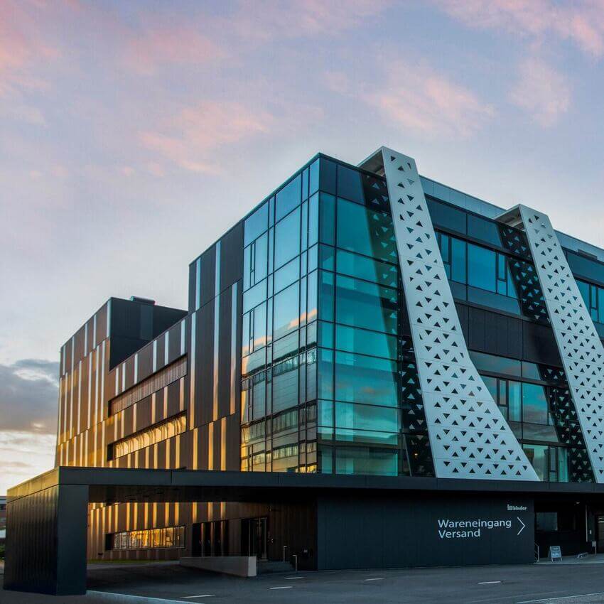 Außenansicht eines modernen Geschäftsgebäudes mit Glasfassade, Fensterreihen und Eingangsbereich