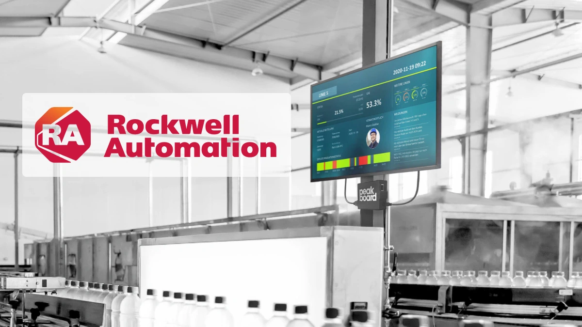 Produktionsumgebung mit Digitalanzeige von Peakboard, die Echtzeit-Kennzahlen einer Rockwell SPS zeigt – im Vordergrund eine automatisierte Abfülllinie.
