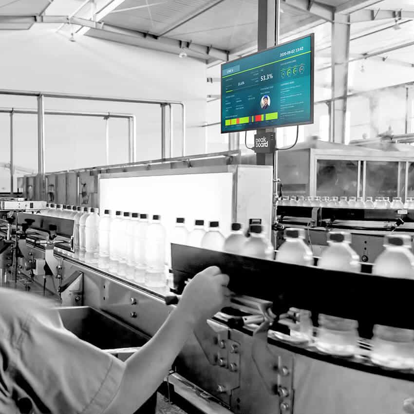 Production employee checks a peakboard dashboard on a production line. The real-time tracking system monitors the efficiency and downtimes of the production machines.
