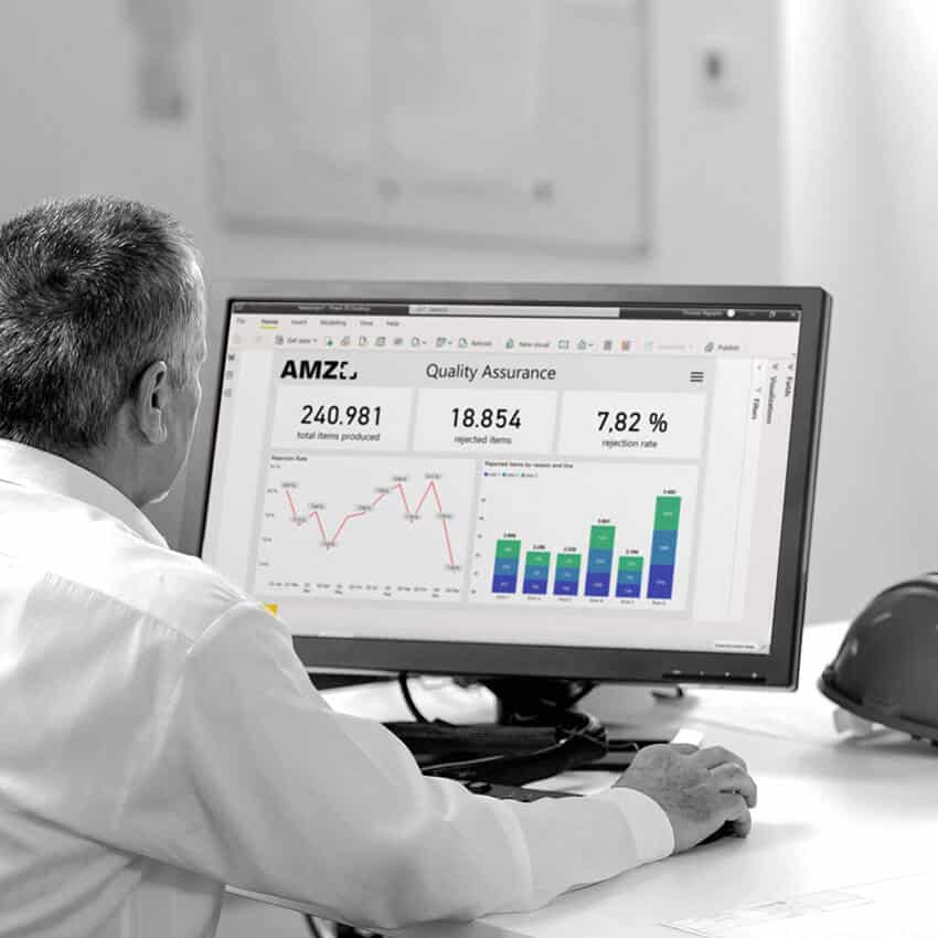 Two employees analyze production and quality data on several screens in the control room. The monitors show a Power BI dashboard with key figures for quality assurance and store floor monitoring.