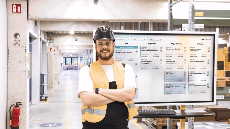 Mitarbeiter vor einer Peakboard-Anwendung für Shopfloor-Meetings mit Aufgabenstatus und Maßnahmen.