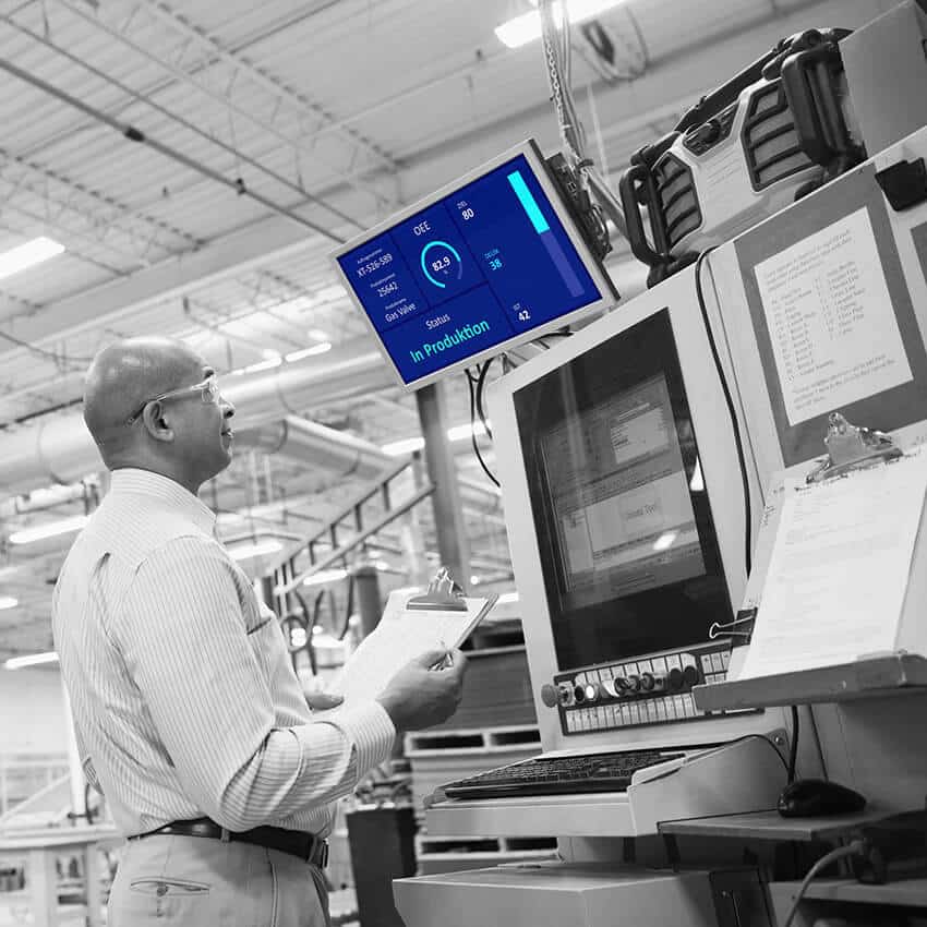 Mitarbeiter überwacht Produktionskennzahlen auf einem Lean Management Board zur Prozessoptimierung.