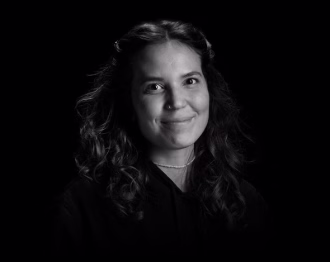 Portrait of Sara, smiling employee in a modern office.