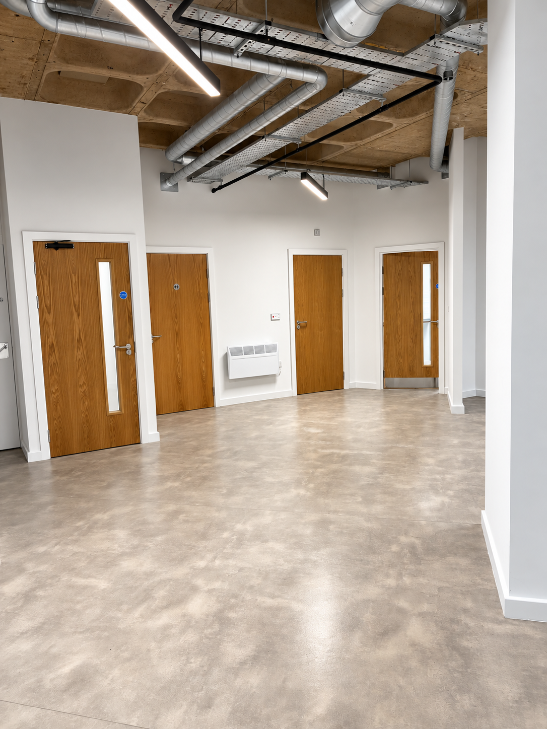 The completed space combines clean modern finishes with exposed ductwork, services and the original concrete soffit, creating the raw industrial character central to Pedestrian’s design brief.
