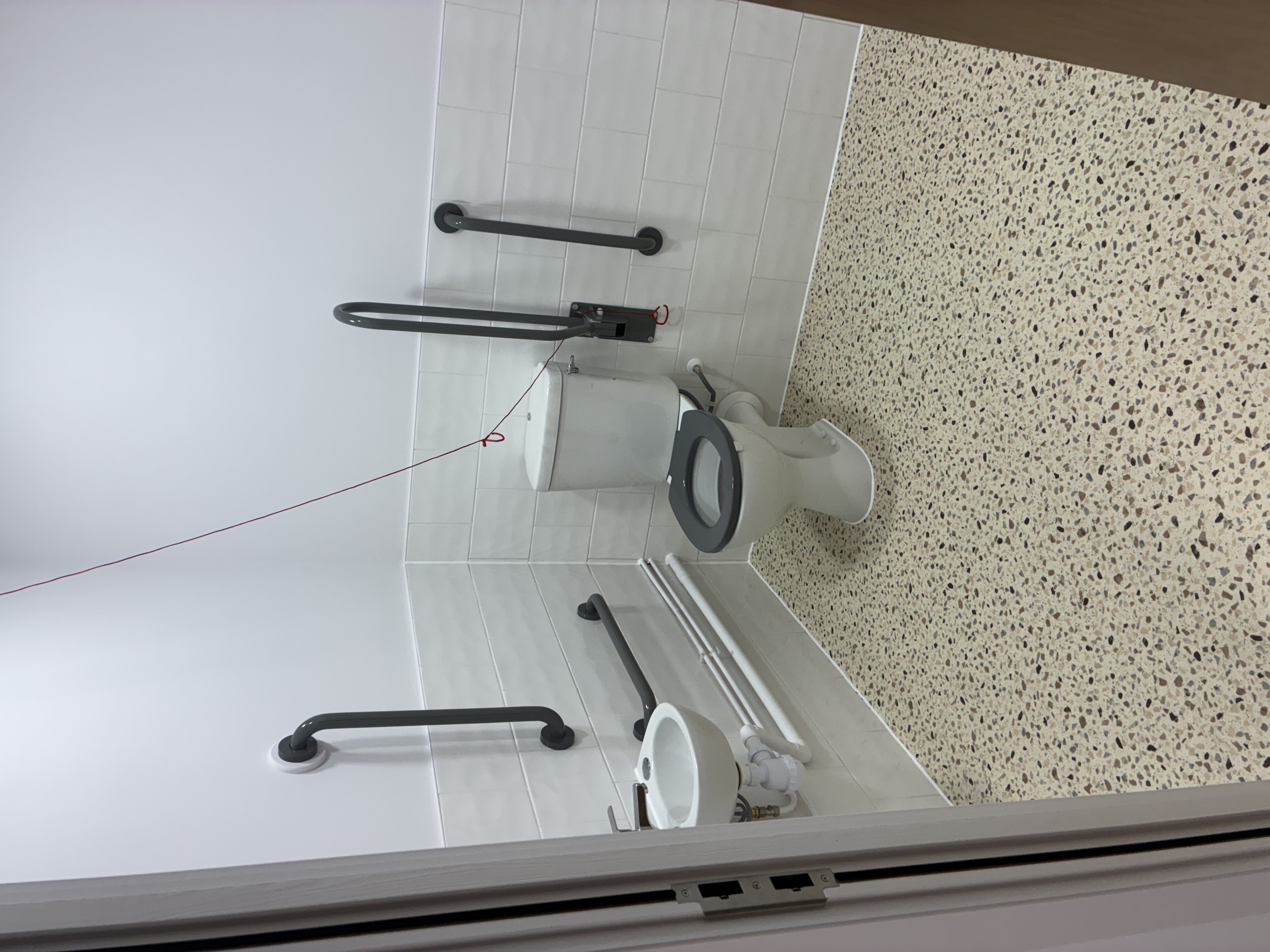 The newly formed accessible WC provides a practical, inclusive facility, finished with contrasting grab rails, tiled walls and a durable terrazzo-style floor.