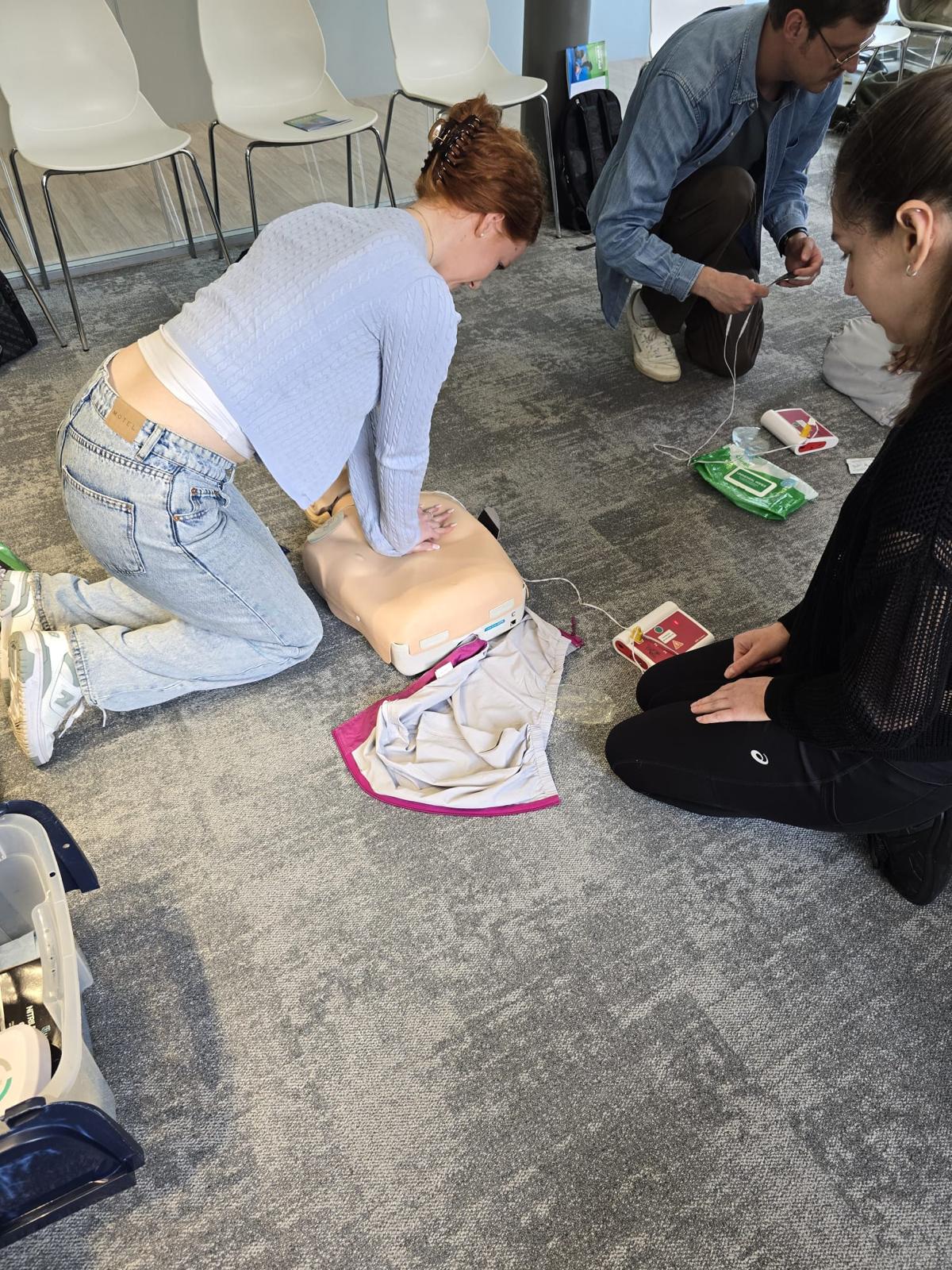 A learner practising CPR on a manikin with a defibrillator during first aid training in Leeds
