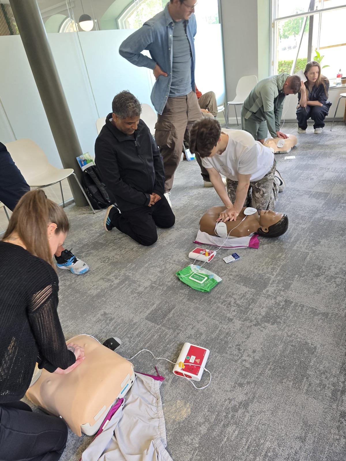 First aid course delegates practising CPR and defibrillator use in a group session
