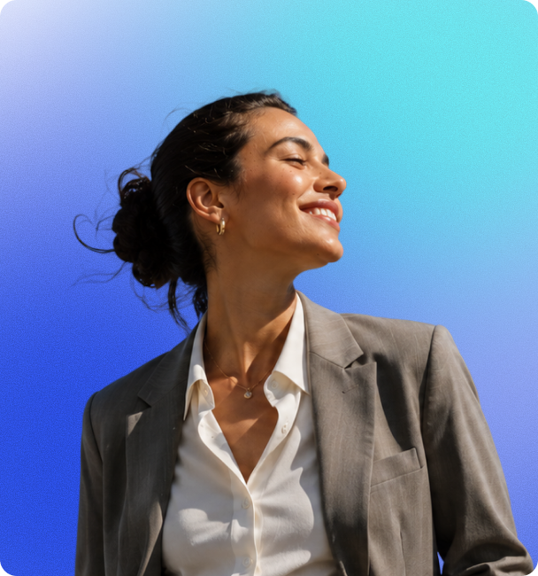 Smiling woman with hair bun wears a gray blazer and white shirt against a blue gradient background.
