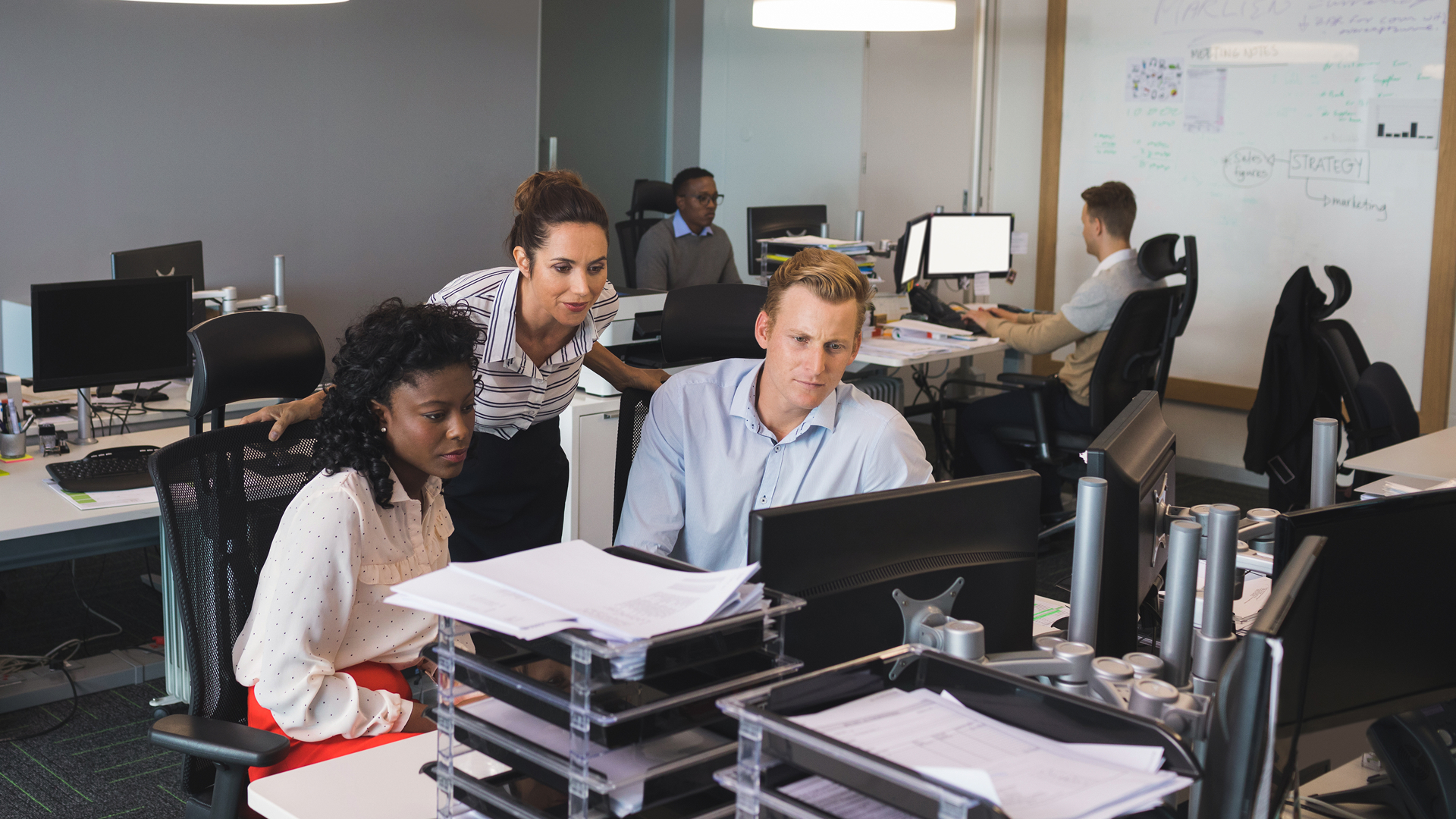 A mature male business owner reviewing paperwork while sitting at desk in an office
