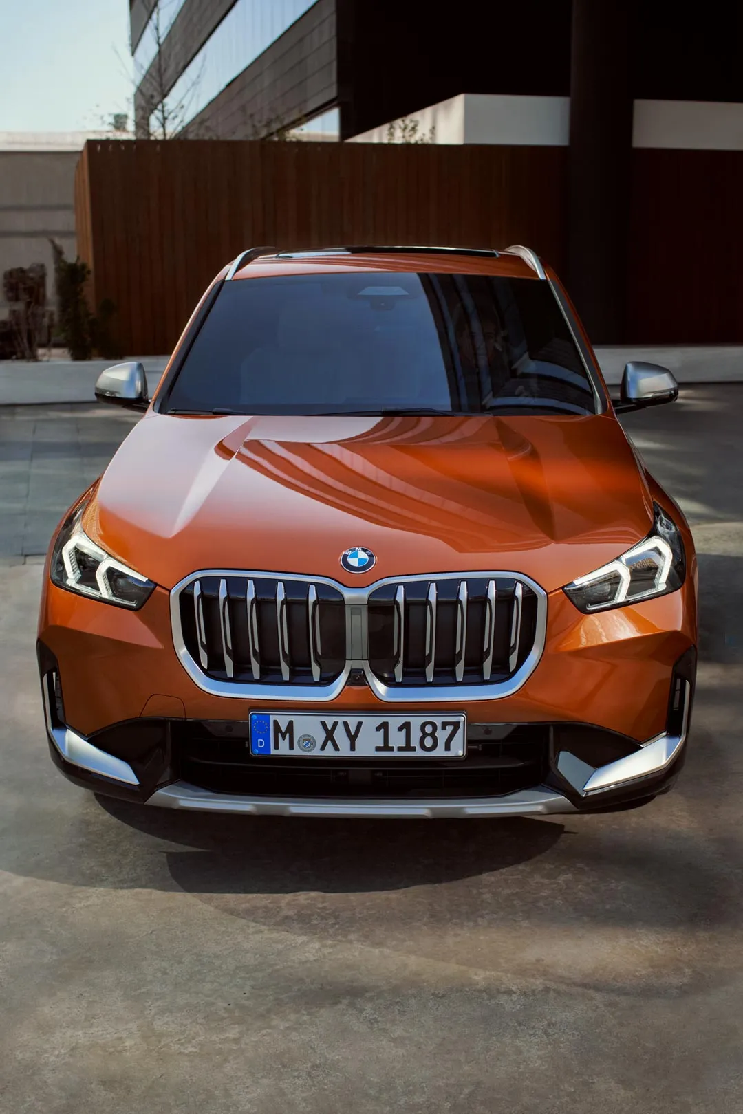 Sportlicher orangefarbener BMW SUV auf einer kurvigen Bergstraße – Fahrspaß und Abenteuer mit MOTORHEIMAT Wagner-Schwarz in Kirchseeon, Traunstein, Altenmarkt, Wasserburg und Oberhaching