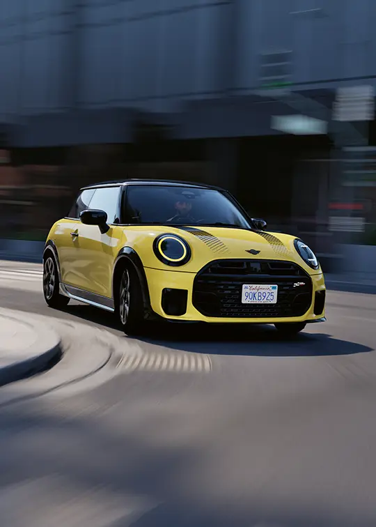Gelber MINI Cooper C fährt dynamisch durch die Stadt – MOTORHEIMAT Wagner-Schwarz in Kirchseeon, Traunstein, Altenmarkt, Wasserburg und Oberhaching