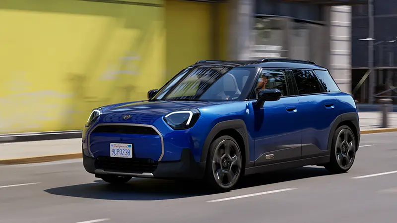 MINI Aceman E in Blau fährt durch die Stadt – MOTORHEIMAT Wagner-Schwarz in Kirchseeon, Traunstein, Altenmarkt, Wasserburg und Oberhaching