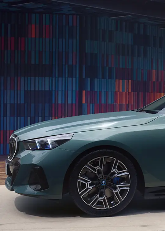 BMW i5 eDrive 40 in grün vor einer modernen Wand – MOTORHEIMAT Wagner-Schwarz in Kirchseeon, Traunstein, Altenmarkt, Wasserburg und Oberhaching