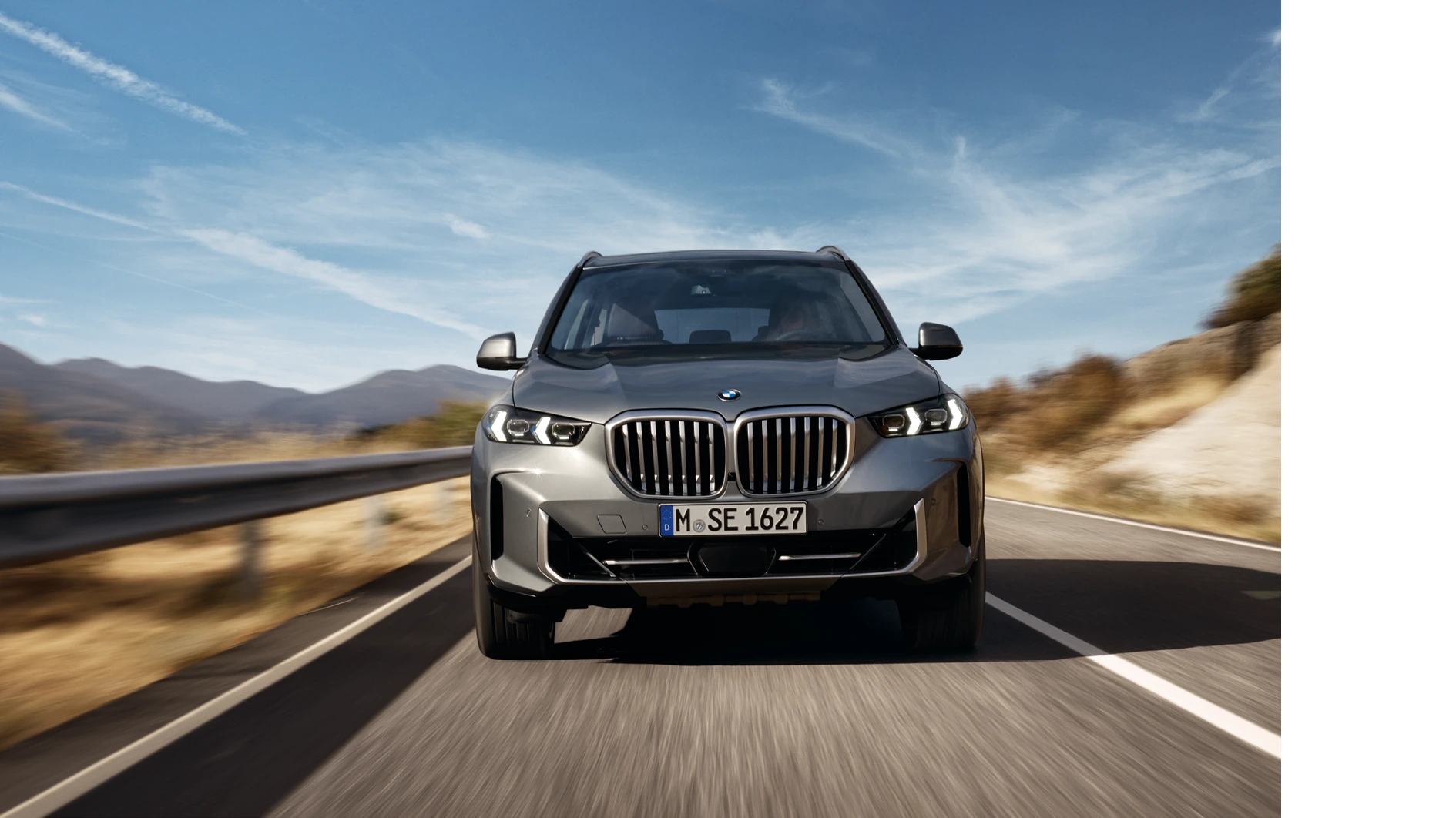 Zwei BMW X Modelle vor moderner Glasfassade, eines in Silber und eines in Petrol-Metallic an der Ladesäule – MOTORHEIMAT Wagner-Schwarz in Kirchseeon, Traunstein, Altenmarkt, Wasserburg und Oberhaching
