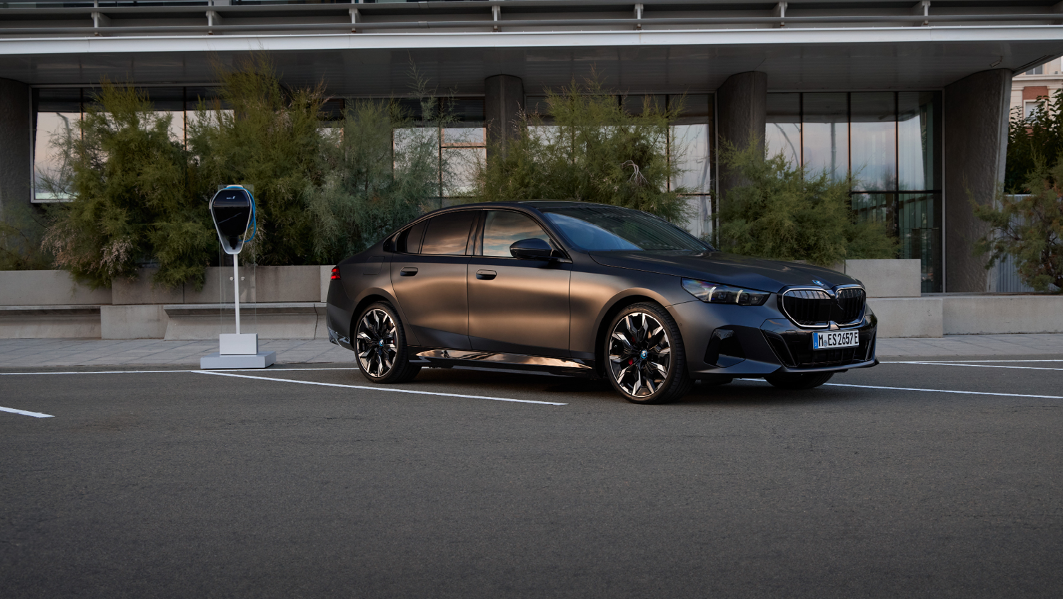 Grüner BMW 5er Touring Plug-in-Hybrid mit sportlicher M-Ausstattung parkt vor moderner Wand – MOTORHEIMAT Wagner-Schwarz in Kirchseeon, Traunstein, Altenmarkt, Wasserburg und Oberhaching