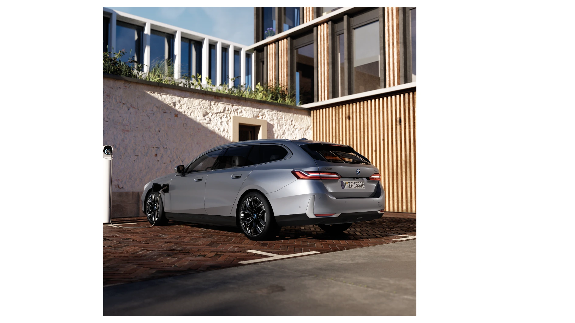 Grüner BMW 5er Touring Plug-in-Hybrid mit sportlicher M-Ausstattung parkt vor moderner Wand – MOTORHEIMAT Wagner-Schwarz in Kirchseeon, Traunstein, Altenmarkt, Wasserburg und Oberhaching