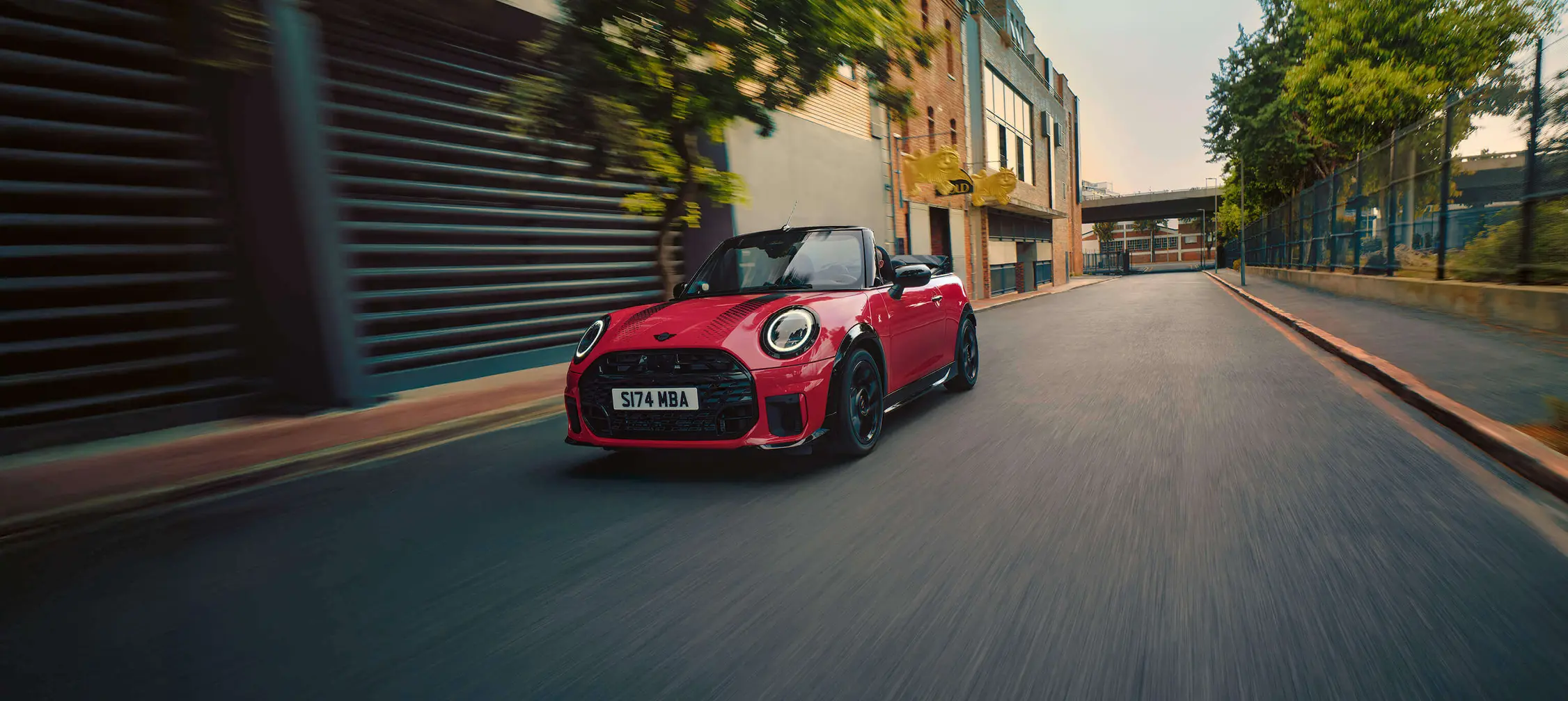 Rotes MINI Cooper C Cabrio mit schwarzen Streifen fährt durch die Stadt – MOTORHEIMAT Wagner-Schwarz in Kirchseeon, Traunstein, Altenmarkt, Wasserburg und Oberhaching
