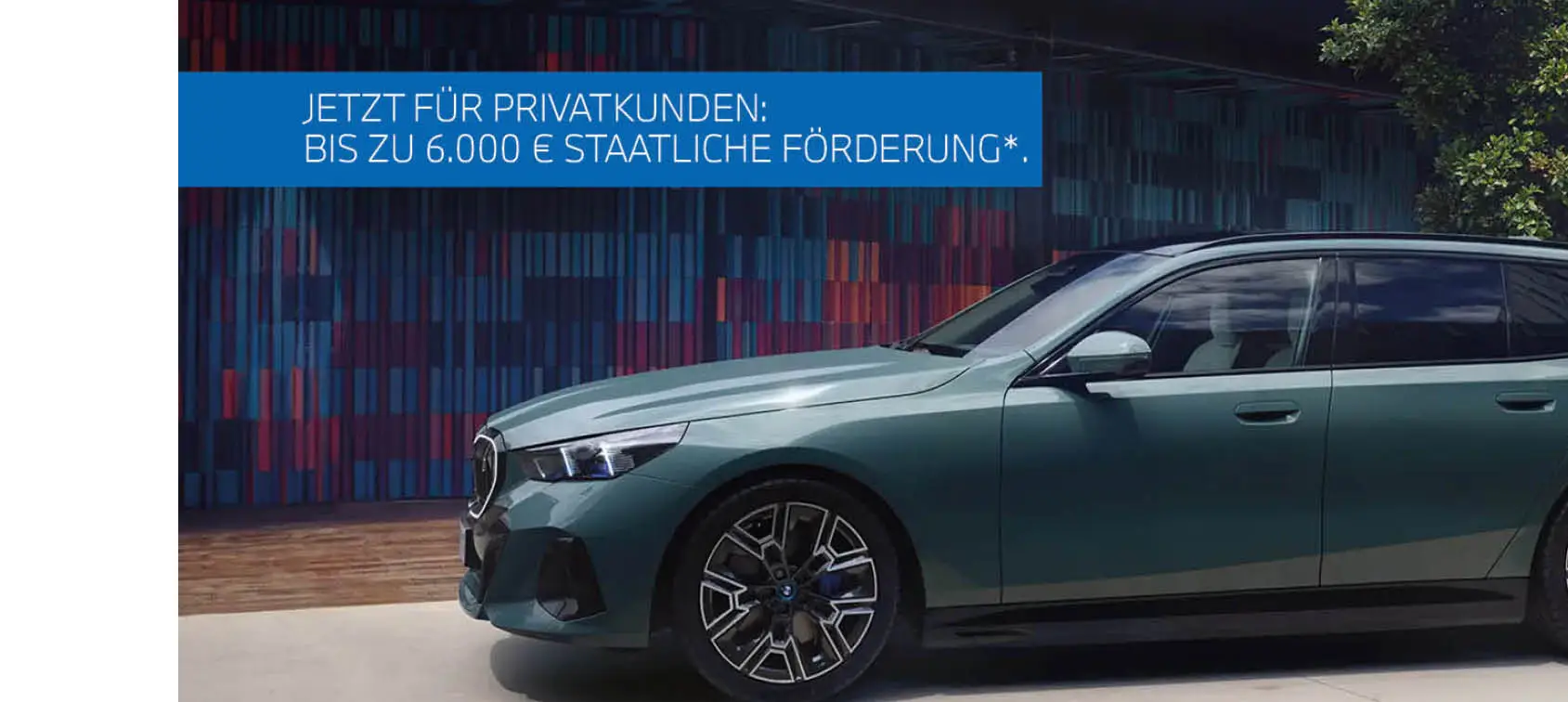 Grüner BMW 5er Touring Plug-in-Hybrid mit sportlicher M-Ausstattung parkt vor moderner Wand – MOTORHEIMAT Wagner-Schwarz in Kirchseeon, Traunstein, Altenmarkt, Wasserburg und Oberhaching