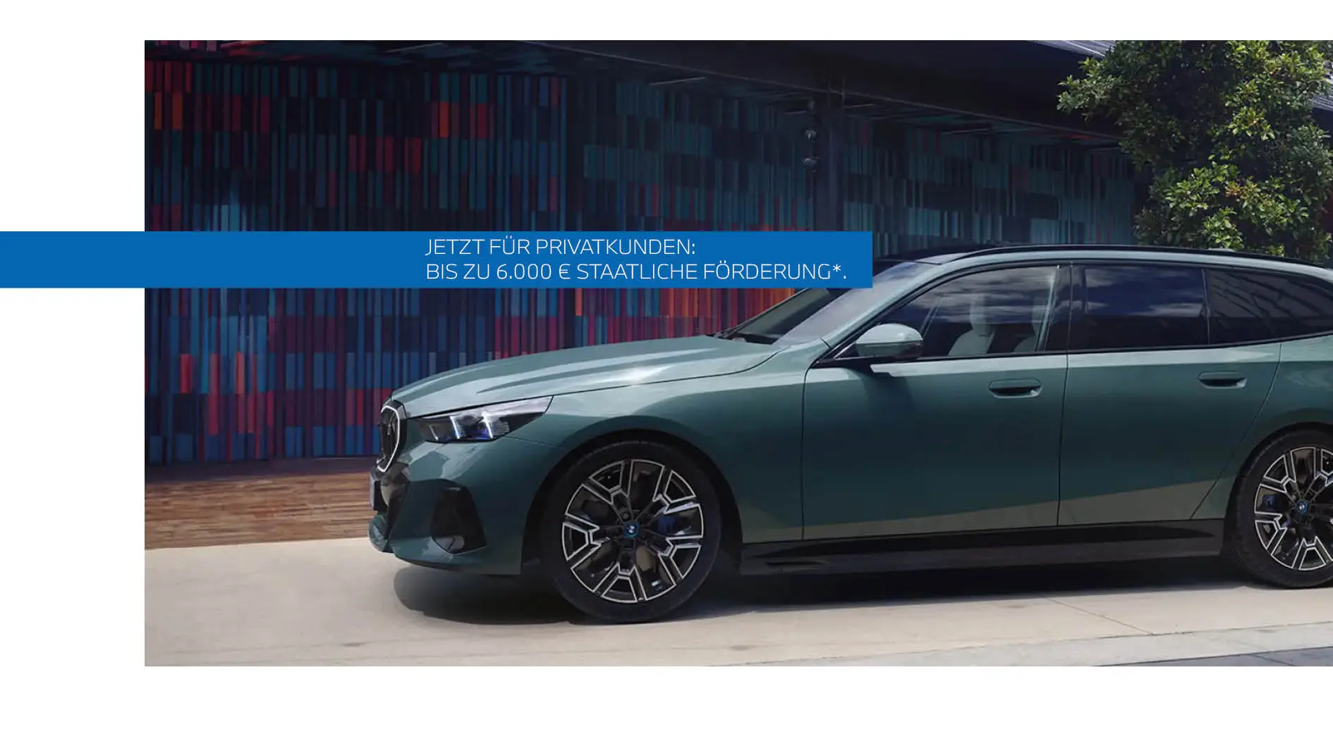 Grüner BMW 5er Touring Plug-in-Hybrid mit sportlicher M-Ausstattung parkt vor moderner Wand – MOTORHEIMAT Wagner-Schwarz in Kirchseeon, Traunstein, Altenmarkt, Wasserburg und Oberhaching