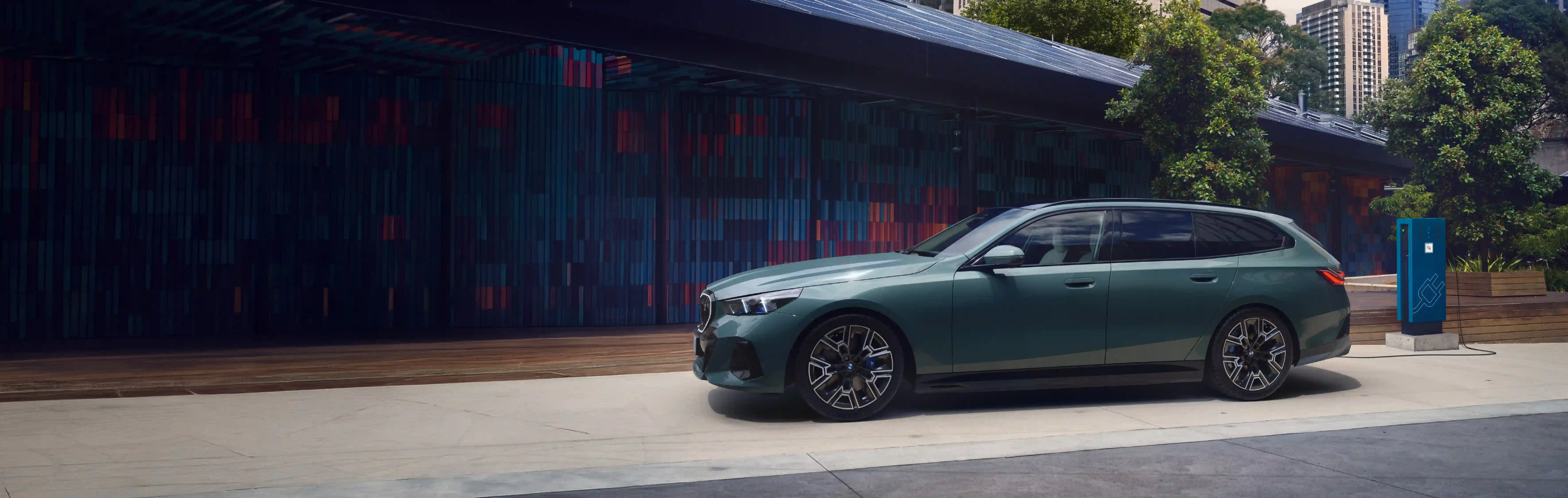 BMW i5 eDrive 40 in grün vor einer modernen Wand – MOTORHEIMAT Wagner-Schwarz in Kirchseeon, Traunstein, Altenmarkt, Wasserburg und Oberhaching