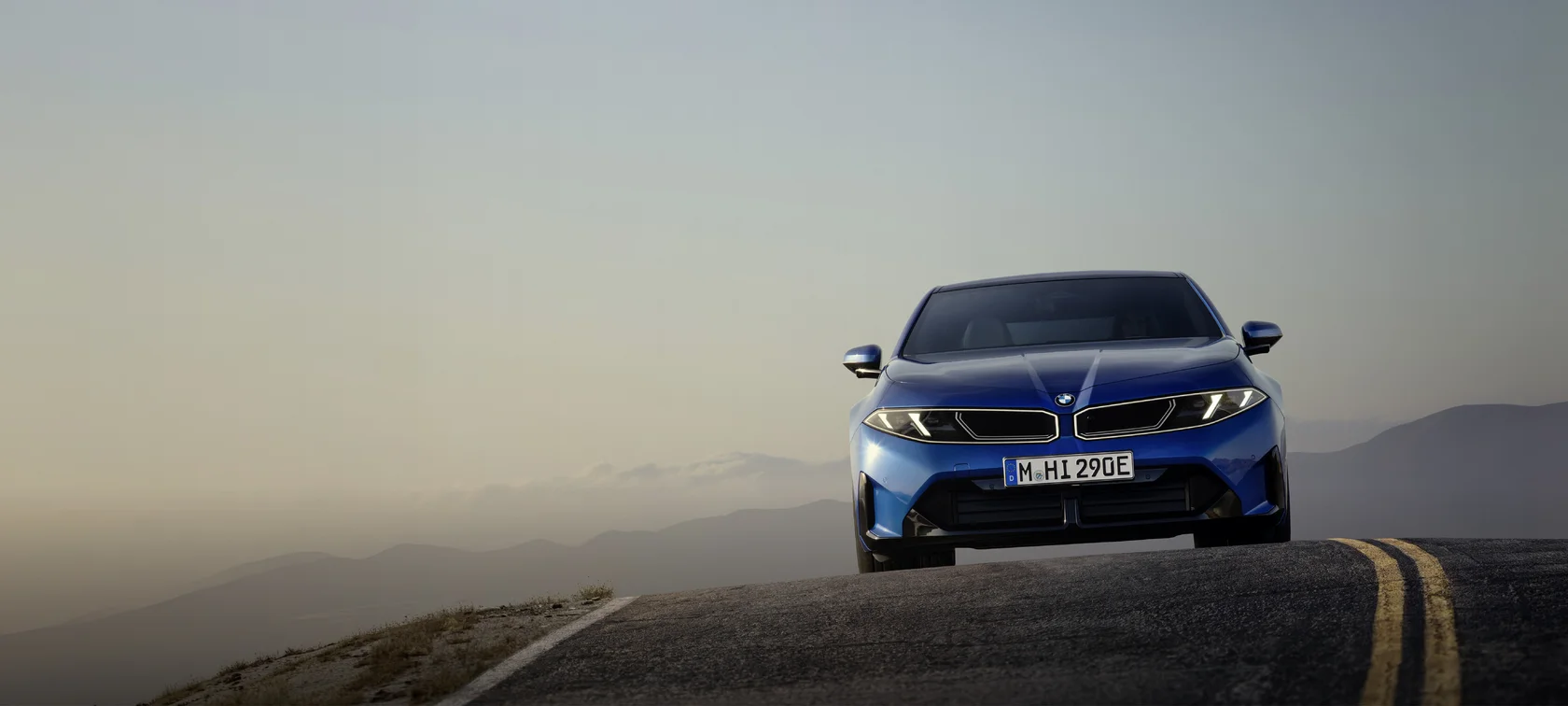 Blauer BMW i3 fährt auf einer Bergstraße in der Abenddämmerung – MOTORHEIMAT Wagner-Schwarz in Kirchseeon, Traunstein, Altenmarkt, Wasserburg und Oberhaching