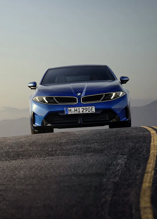Blauer BMW i3 fährt auf einer Bergstraße in der Abenddämmerung – MOTORHEIMAT Wagner-Schwarz in Kirchseeon, Traunstein, Altenmarkt, Wasserburg und Oberhaching