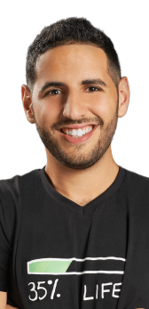 Smiling man with short curly hair and beard wearing a black shirt with a graphic and text that reads '35% LIFE'.